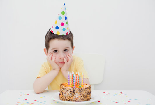 Child in party hat birthday cake
