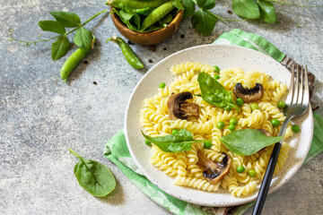 Healthy eating. Pasta fusilli with mushrooms, spinach and green peas on stone table. Vegetarian vegetable mushrooms pasta. Diet menu.
