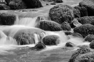 Fluss in einem Gebirge, der über Steine fließt, Langzeitbelichtung 