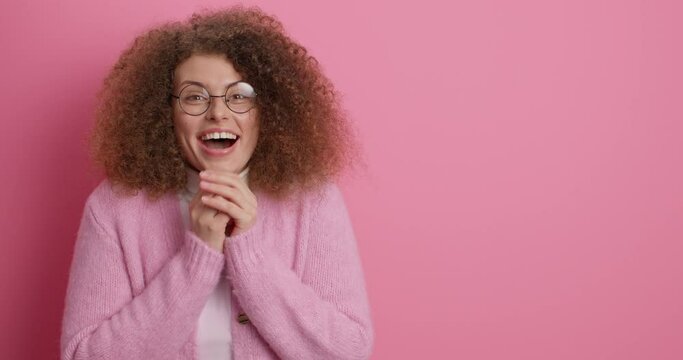 Pretty amazed European woman looks with happy surprised expression aside says wow notices something unbelievable dressed in casual clothes isolated over pink background blank copy space aside