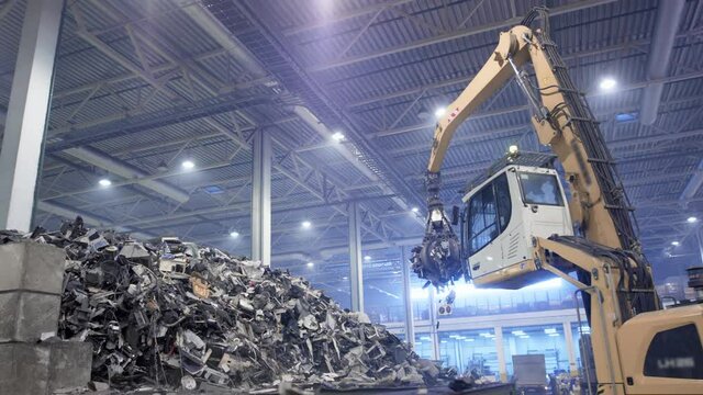 Excavator claw grabs trash on a heap in a landfill