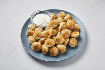 Fried dumplings with sour cream and spices on a white plate
