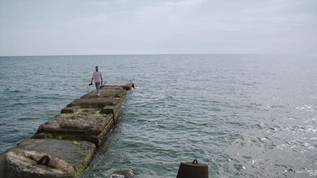 Man with Photo Camera Walks on The Sea Pier