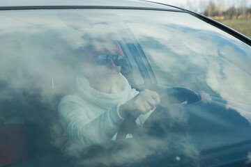 Portrait of a beautiful woman driving a car. A woman often drives out of town by car. In the...