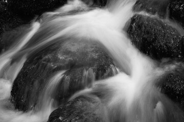 Fluss in einem Gebirge, der über Steine fließt, Langzeitbelichtung 