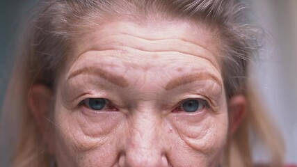 Close up on blue eyes of an elderly woman with wrinkled skin. Depression at old age. High quality 4k footage