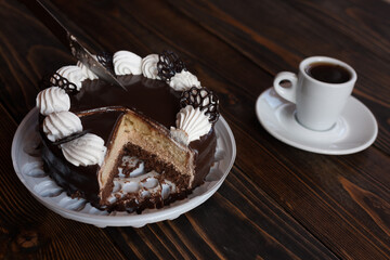A cup of aromatic black coffee and chocolate cake on an old wooden table. 