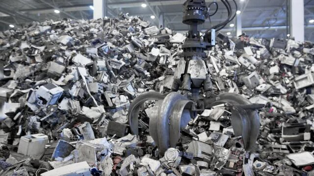 Scrap Yard Excavator picks up trash from a heap in a landfill