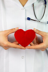 Female doctors's hands holding red heart and putting stethoscope's head close to it. Medical help or insurance concept. Cardiology care and health. Heart surgery and resuscitation concept 