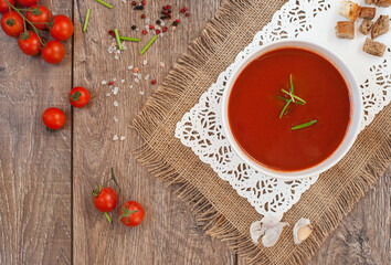 Delicious tomatoes soup on dark rustic wooden table.