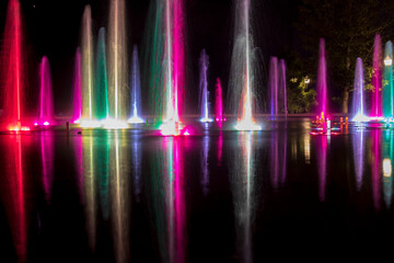 Naklejka na ściany i meble At night, this fountain becomes a grand theater with brightly lit water jets changing colours and moving in tune with music