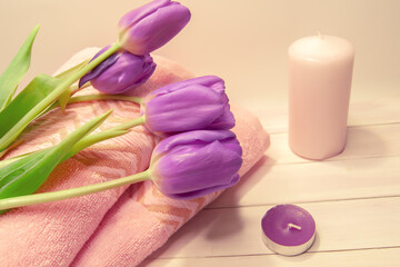 Spa still life - tulips, candles, towels on a white wooden background. Beige, pink, lilac, purple and white tones.