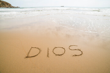 Words written on the sand on the beach, the sign says ... happiness, sea, be yourself, universe, god, travel, happy, love