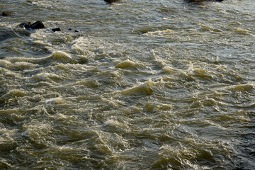 Closeup shot of dirty water flowing on a river, Waves of water of the river and the sea meet each other during high tide and low tide.