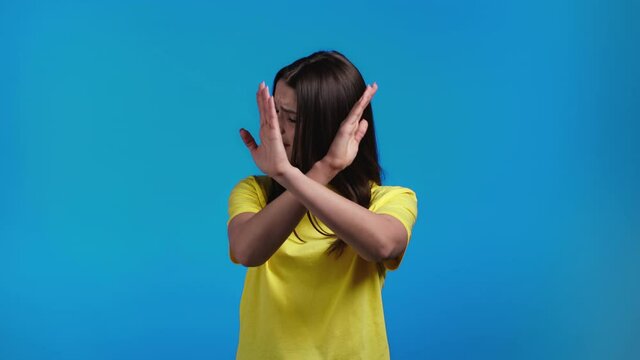 Pretty girl disapproving with no crossing hands sign make basta, negation, enough gesture. Denying, Rejecting, Disagree, Portrait of pretty girl on blue background