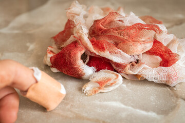 A man with a wounded finger after being cut with a knife in the kitchen against the background of bloody bandage