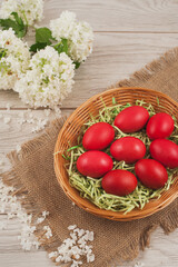 Traditional red Easter eggs in a basket on rustic wood background.