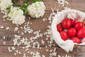 Traditional red Easter eggs in a basket on rustic wood background.