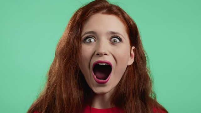 Pretty woman is very glad, she screaming WOW loud. Concept of sales, profitable offer. Excited happy lady on green studio background.