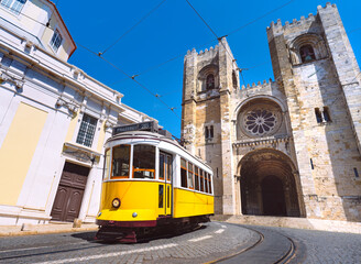 Lisbon city old town and famous yellow tram 28 in front of Santa Maria cathedral on a sunny summer day. Trams in Lisbon, Portugal. Tourist attraction