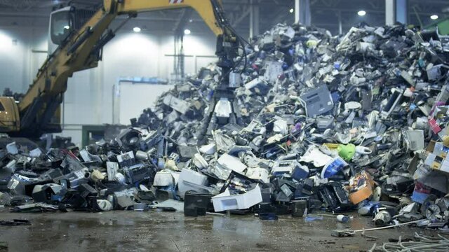 Excavator claw grabs trash on a heap in a landfill