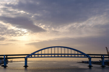 早朝、六甲大橋から大阪湾を望む。高速道路の橋の上に日が昇り、当がオレンジ色に染まる。