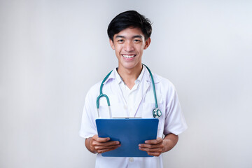 Smiling Young Asian medical doctor holding a medical report clipboard. Male doctor smiling holding clipboard