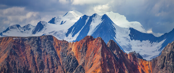 Naklejka premium Colored rocks and snow-capped peaks. Cloudy weather and morning light. 