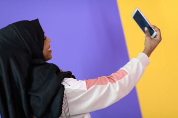 african muslim woman with a beautiful smile takes a selfie with a cell phone