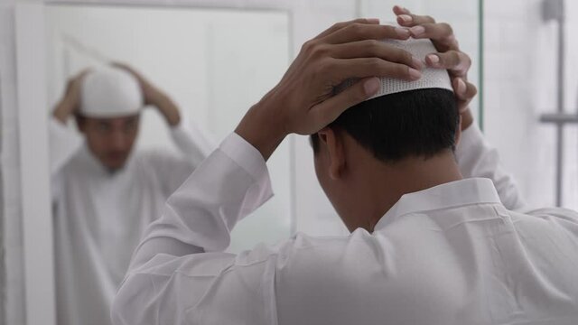 muslim asian man looking at mirror and get dressed before going to the mosque
