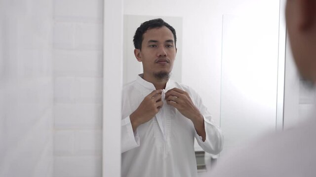 muslim asian man looking at mirror and get dressed before going to the mosque