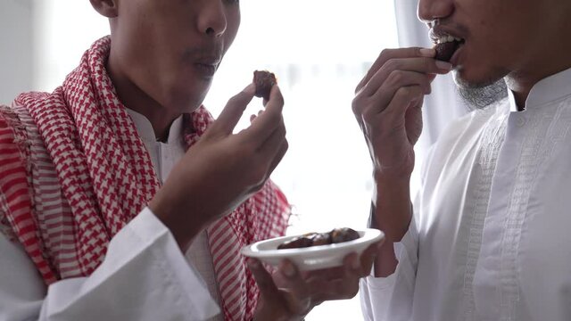 close up of muslim sharing a bowl of dates while enjoying iftar dinner together during a ramadan feast at home