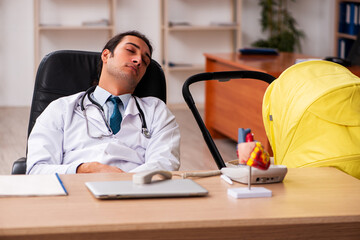 Young male doctor looking after new born in the clinic