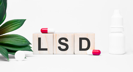 LSD the word is written on wooden cubes,plant and red pills,on white background