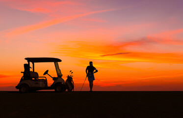 Silhouette lady golfer standing on golf course and golf cart with sun sky twilight background.