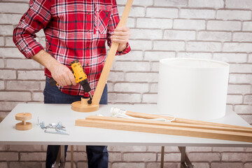 Handyman assembling furniture, floor lamp at home. The concept of DIY.