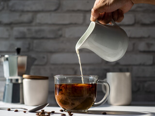 pouring cream milk into cup of coffee