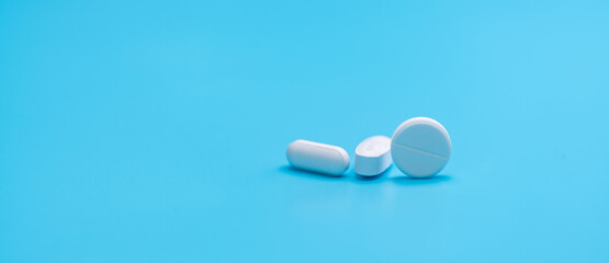 Round white tablets pills and oval tablets pills on blue background. Pharmacy shop banner....