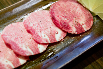 Atsui Tan, Ox tongue sliced served on a black tray with lemon.
