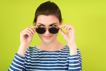 woman in sunglasses posing in front of a green background