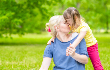 Happy family. Mother and little girl with special needs have a fun in a summer park. Empty space for text