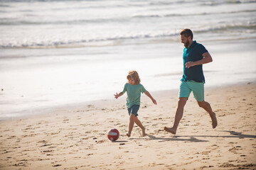 Daddy with kid boy playing on a summer day. Father and son play soccer or football on the beach. Lifestyle and family vacation, happiness men concept.