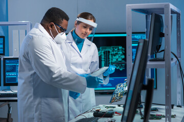 Diverse team of microelectronic engineers discuss current developments in a science lab. Workplace...