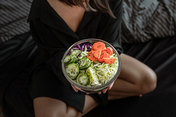 Woman in pajamas in bed with fresh vegetarian vegetable salad.
