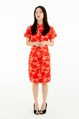 Full body shot of Chinese beautiful woman with long black hairs is standing, smiling against white background. She wearing red traditional dress that has pattern of gold flower.