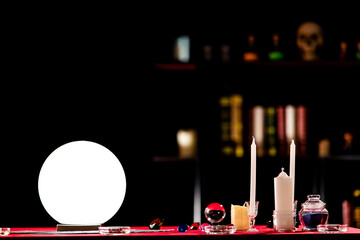 Working table for a fortune teller in a dark room. It consist of a white shining ball, candles,...