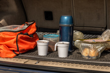 Cups of tea, a thermos, food in the trunk of the car. A snack during a car travel. Stopping for a rest and snack. Pitstop.