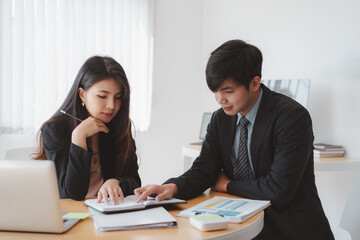 Two asian businesspeople in suits discussing corporate financial report,board of directors planning project in the office.