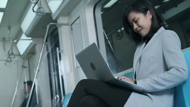 Businesswomen discussing work from their laptops on the electric train in the middle of the night.