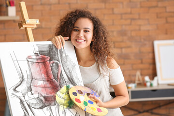 Beautiful female African-American artist painting in studio